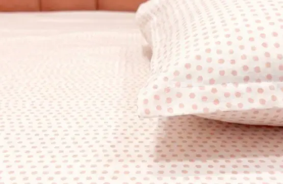 Close-up of Blush Dots Cotton King Size Bedsheet showing soft coral pink polka dot pattern on white 100% cotton fabric with textured weave