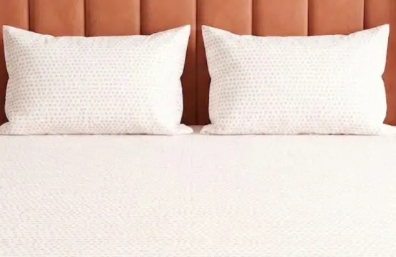 Blush Dots Cotton King Size Bedsheet styled on king bed with matching pillowcases featuring coral pink polka dots against terracotta velvet headboard