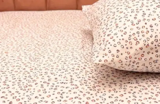 Close-up detail of Blush Safari bedsheet showing pink, coral, and purple leopard spots on soft 100% cotton fabric with matching pillow