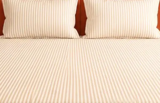 Sandy Stripe Luxe King Size Cotton Bedsheet Set styled on bed with matching pillows against orange upholstered headboard